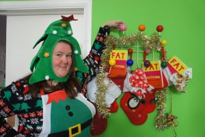 Charlotte stands with Fat Activism books stuffed into stockings hanging from the wall