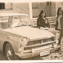 Two women stand next to a car